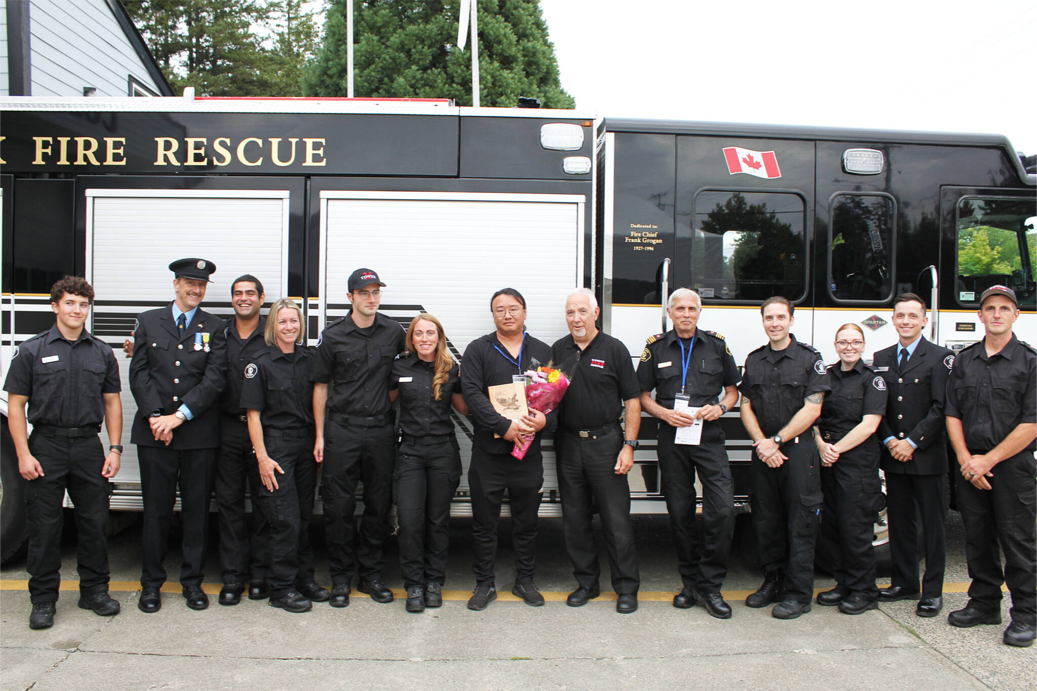 Junyi Liu, 41, saved an elderly woman from the flames during the Comox Esso fire in May 2023. A few months later, he was awarded the Courage & Bravery Local Hero Award. Liu (middle) poses surrounded by firefighters of the Comox Fire Rescue during the award ceremony on Sept. 6. (Connor McDowell / Comox Valley Record)