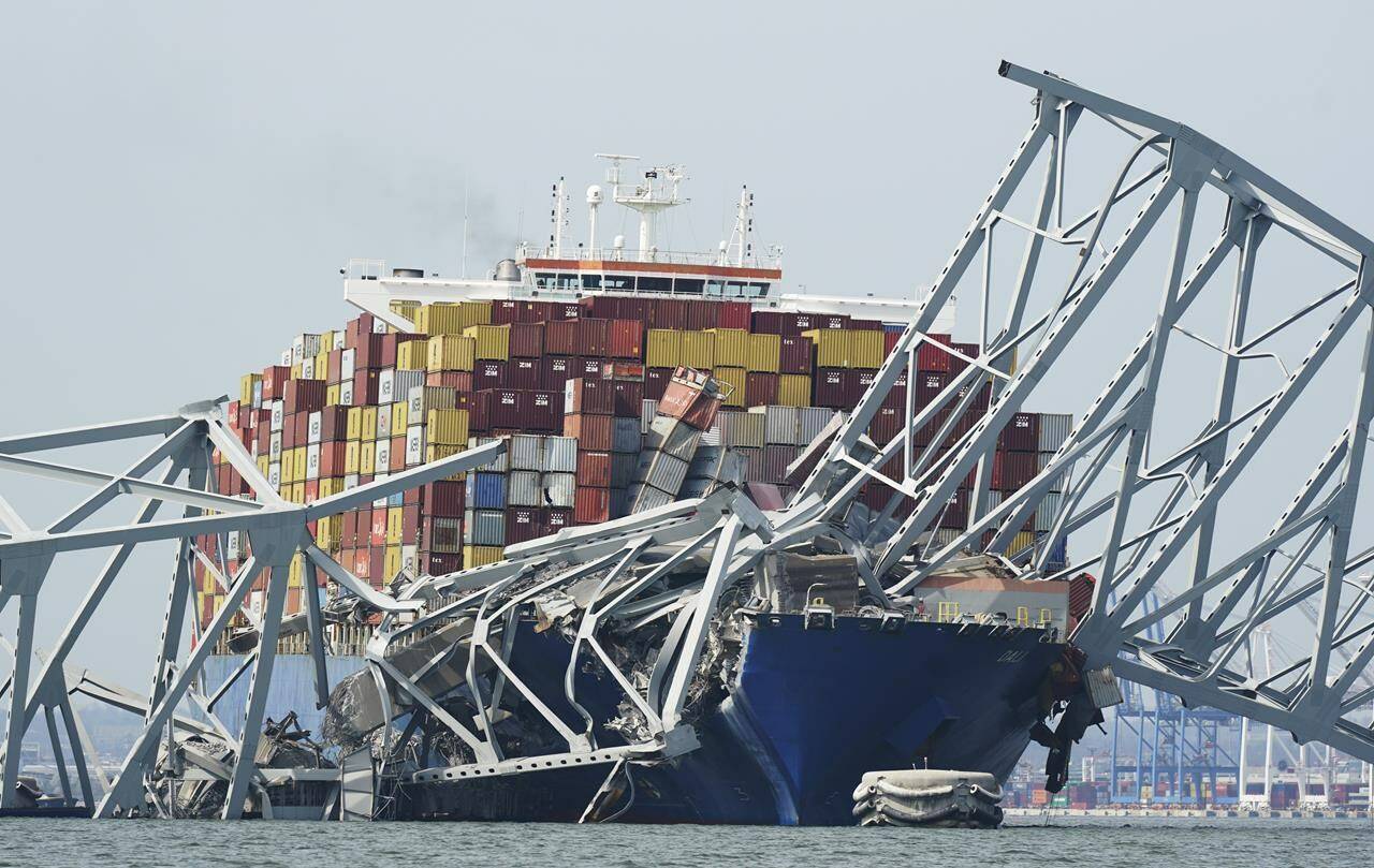 A cargo ship is stuck under the part of the structure of the Francis Scott Key Bridge after the ship hit the bridge Tuesday March 26, 2024, in Baltimore, Md. (AP Photo/Steve Helber)