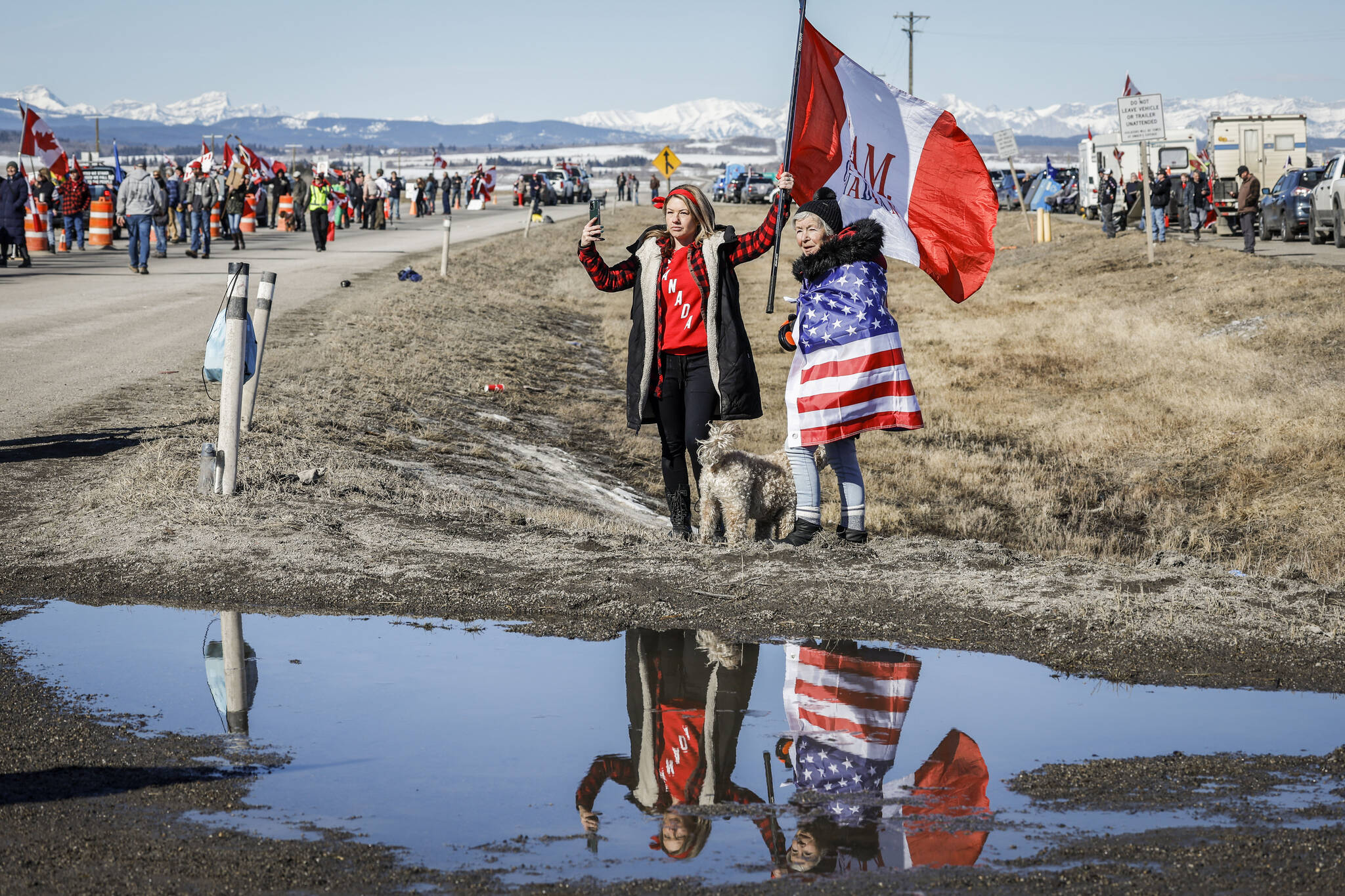 Anti-carbon tax protesters wave signs and chant slogans as they block a westbound lane of the Trans Canada highway near Cochrane, Alta., Monday, April 1, 2024.THE CANADIAN PRESS/Jeff McIntosh