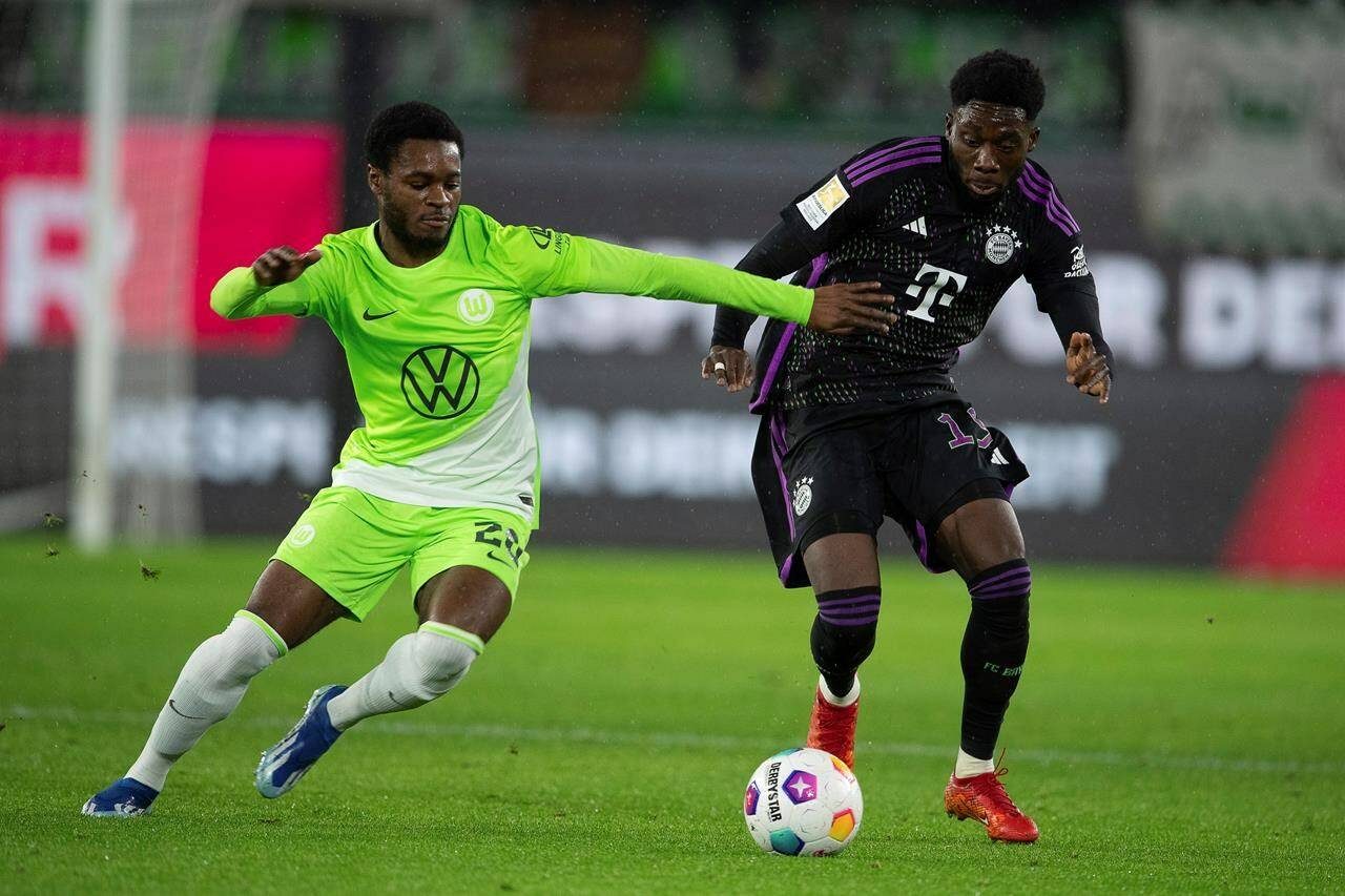 Wolfsburg’s Ridle Baku, left, and Bayern’s Alphonso Davies battle for the ball during the German Bundesliga soccer match between VfL Wolfsburg and Bayern Munich at the Volkswagen Arena, Wolfsburg, Germany, Wednesday, Dec. 20, 2023. Count the Vancouver Whitecaps among those watching Alphonso future with Bayern Munich with interest. The Whitecaps will benefit from any future sale, thanks to a sell-on clause negotiated in the Canadian star’s sale to the German powerhouse in July 2018. THE CANADIAN PRESS/AP-Swen Pfortner/dpa via AP
