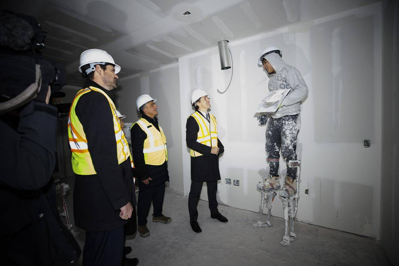 Prime Minister Justin Trudeau meets a drywall worker with Housing Minister Sean Fraser (left) as they tour an under-construction condo tower in midtown Toronto, Wednesday, April 3, 2024. THE CANADIAN PRESS/Cole Burston