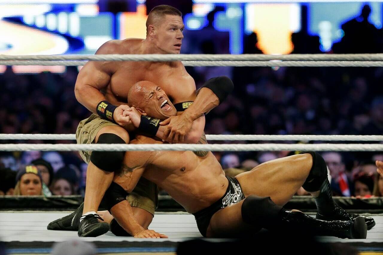 FILE - Wrestler John Cena, top, chokes Dwayne “The Rock” Johnson at a Wrestlemania event, April 7, 2013, in East Rutherford, N.J. Dwayne “The Rock” Johnson is back to perform in one of the main events this weekend’s WrestleMania in Philadelphia (AP Photo/Mel Evans, File)