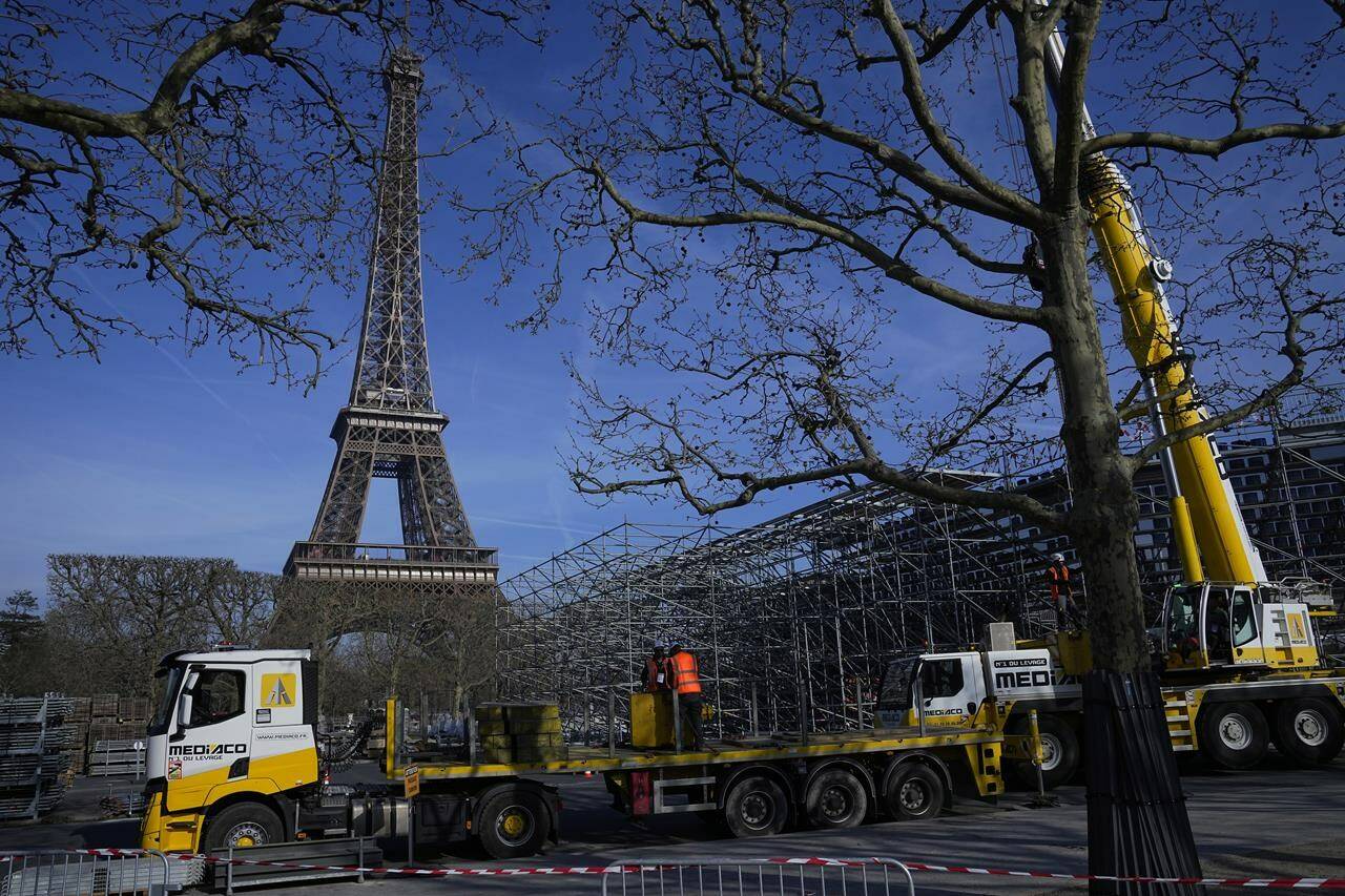Workers build the stands for the upcoming summer Olympic Games on the Champ-de-Mars, just beside the Eiffel Tower, Friday, March 22, 2024 in Paris.The RCMP will be part of an international policing effort to keep the Olympics in Paris safe this summer. THE CANADIAN PRESS/AP/Michel Euler