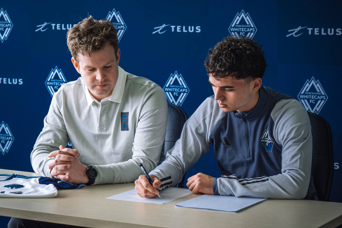 Seventeen-year-old Comox soccer sensation Liam Mackenzie signs a professional contract with the Vancouver Whitecaps as Quinn Thompson, Whitecaps FC senior director of player personnel, first team operations looks on. Photo by Noah Celebiler/Vancouver Whitecaps FC