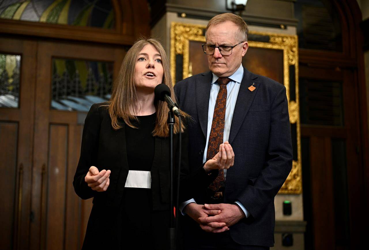 NDP MPs Laurel Collins and Peter Julian speak in the Foyer of the House of Commons before Question Period, on Parliament Hill in Ottawa on Wednesday, April 10, 2024. The New Democrats say they are supporting a Conservative motion that calls on Prime Minister Justin Trudeau to defend his carbon pricing policy in a televised “emergency meeting” with the country’s premiers. THE CANADIAN PRESS/Justin Tang
