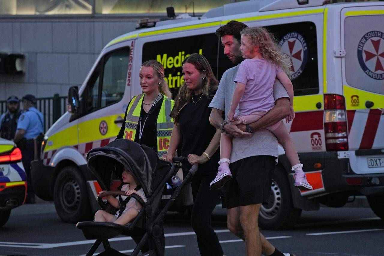 People are led out from the Westfield Shopping Centre where multiple people were stabbed in Sydney, Saturday, April 13, 2024. (AP Photo/Rick Rycroft)