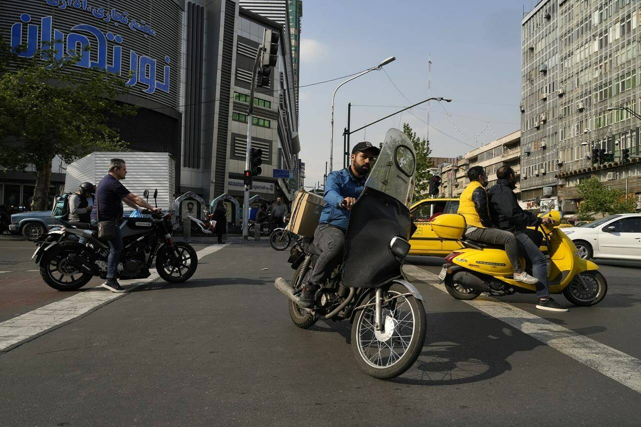 Motorbikes cross an intersection in downtown Tehran, Iran, Sunday, April 14, 2024. Israel on Sunday hailed its air defenses in the face of an unprecedented attack by Iran, saying the systems thwarted 99% of the more than 300 drones and missiles launched toward its territory. (AP Photo/Vahid Salemi)