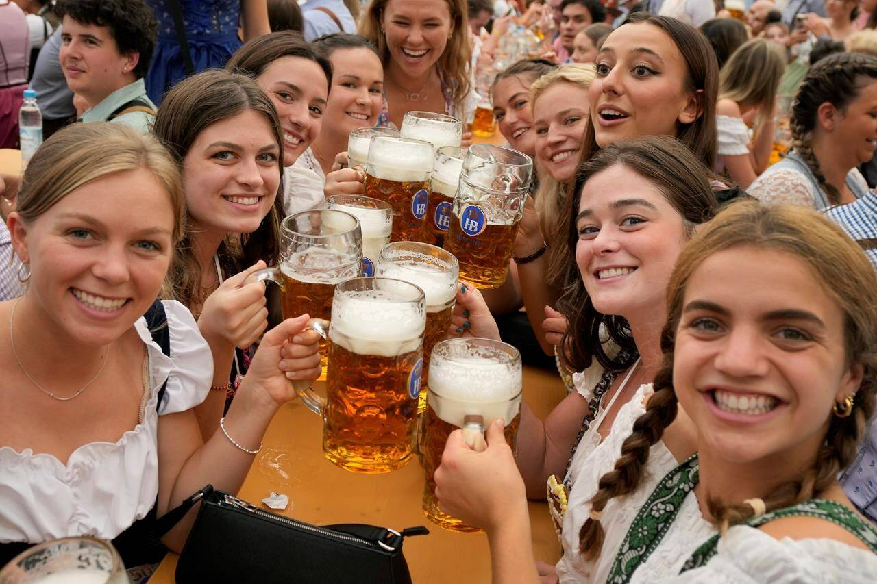 FILE - Women with glasses of beer pose for a photo on day one of the 188th ‘Oktoberfest’ beer festival in Munich, Germany, Saturday, Sept. 16, 2023. The southern German state of Bavaria will ban the smoking of cannabis at public festivals, inside beer gardens, and even at the world’s most popular beer festival, the Oktoberfest. (AP Photo/Matthias Schrader, File)