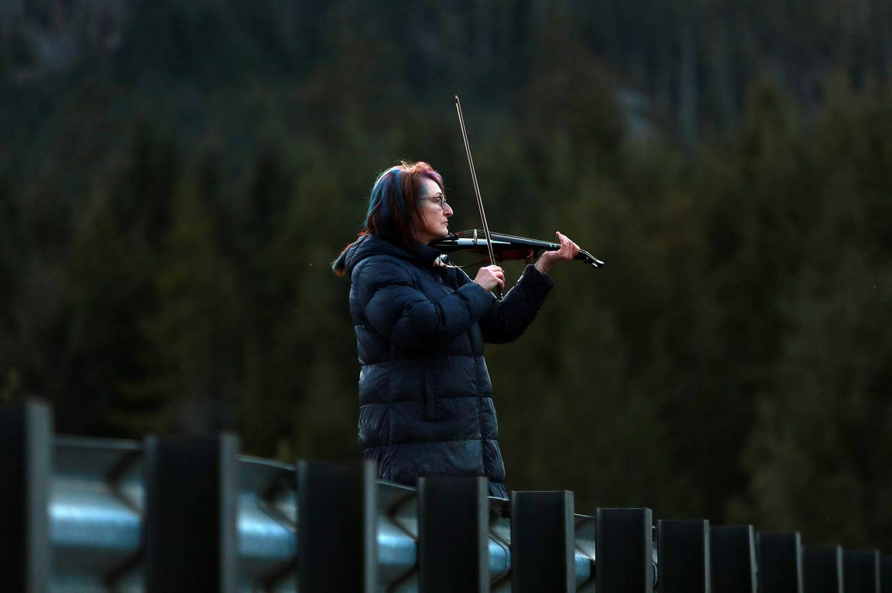 Carol Love plays “Tennessee Whiskey” on her violin at a todal lagoon near Zeballos, B.C., on Wednesday, April 17, 2024. The Nanaimo, B.C., woman says she is serenading a killer whale calf, hoping to entice the orca to leave the remote lagoon where she has been trapped alone for almost four weeks. THE CANADIAN PRESS/Chad Hipolito
