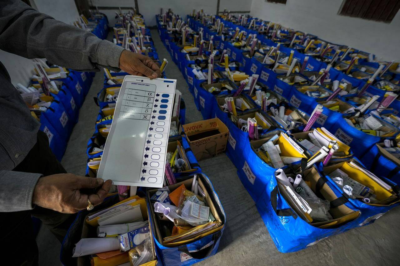 An official holds a mock ballot paper as he prepares bags of election material to be distributed along with the Electronic Voting Machines (EVMs) ahead of the national parliamentary elections in Jorhat, India, Wednesday, April 17, 2024. THE CANADIAN PRESS/AP/Anupam Nath