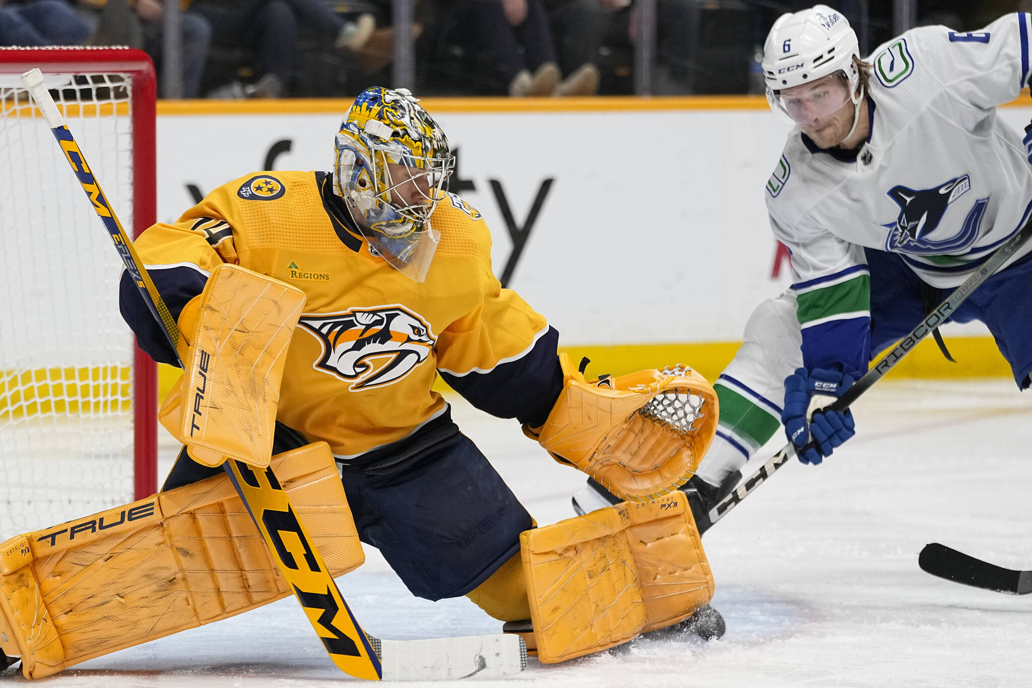 Nashville Predators goaltender Juuse Saros (74) defends the goal against the Vancouver Canucks right wing Brock Boeser (6) during the third period of an NHL hockey game Tuesday, Dec. 19, 2023, in Nashville, Tenn. The Canucks won 5-2. (AP Photo/George Walker IV)