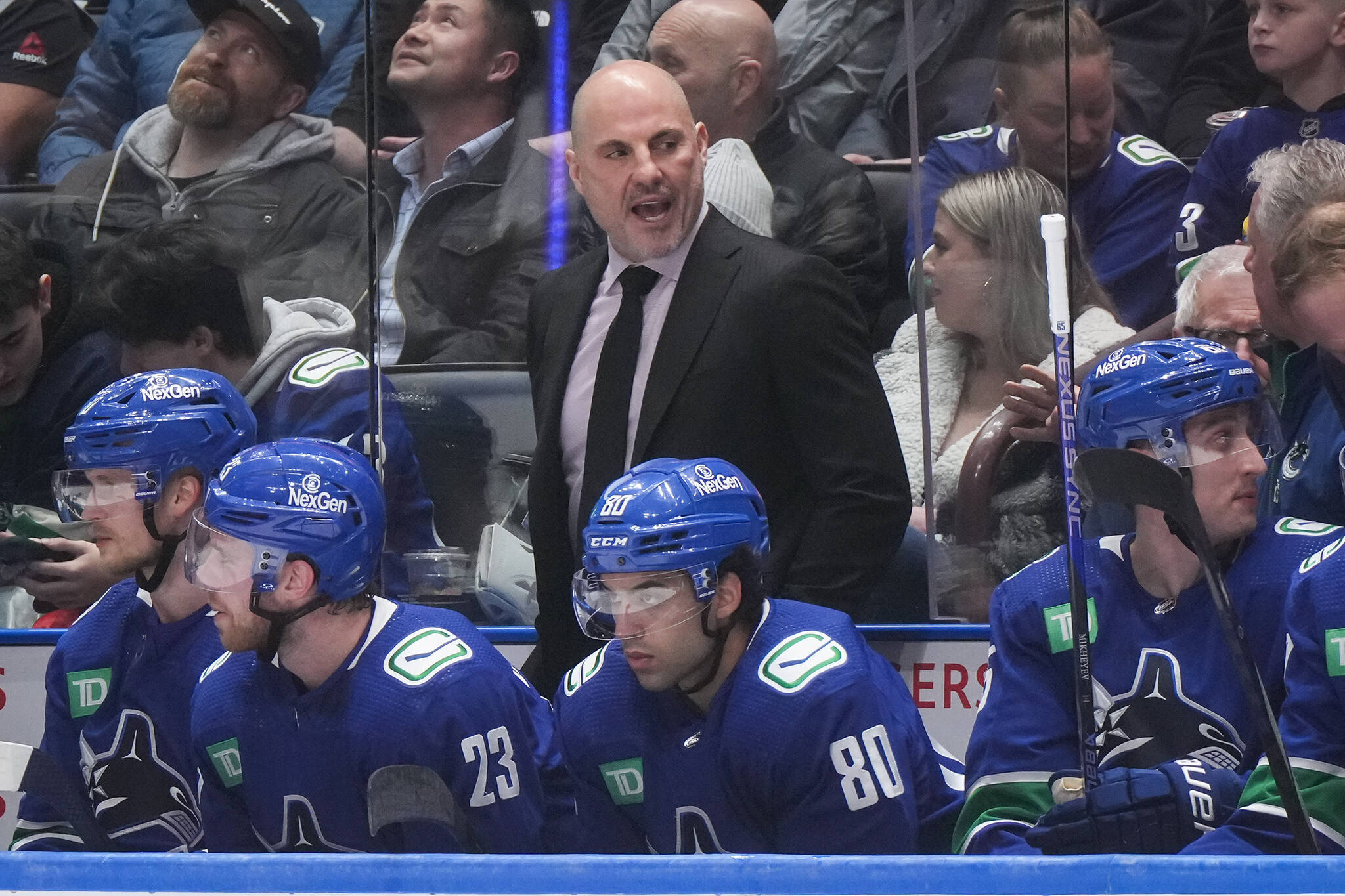 Vancouver Canucks head coach Rick Tocchet stands on the bench behind Elias Pettersson, front from left to right, Elias Lindholm, Arshdeep Bains and Ilya Mikheyev during the first period of an NHL hockey game against the Pittsburgh Penguins, in Vancouver, on Tuesday, February 27, 2024. THE CANADIAN PRESS/Darryl Dyck