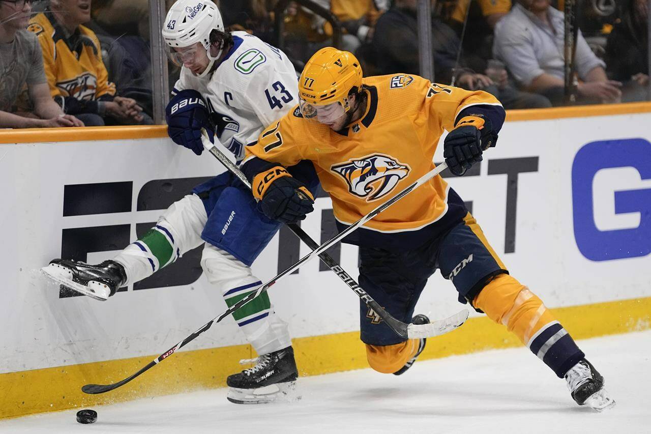Vancouver Canucks defenseman Quinn Hughes (43) and Nashville Predators right wing Luke Evangelista (77) battle for the puck during the second period in Game 3 of an NHL hockey Stanley Cup first-round playoff series Friday, April 26, 2024, in Nashville, Tenn. (AP Photo/George Walker IV)