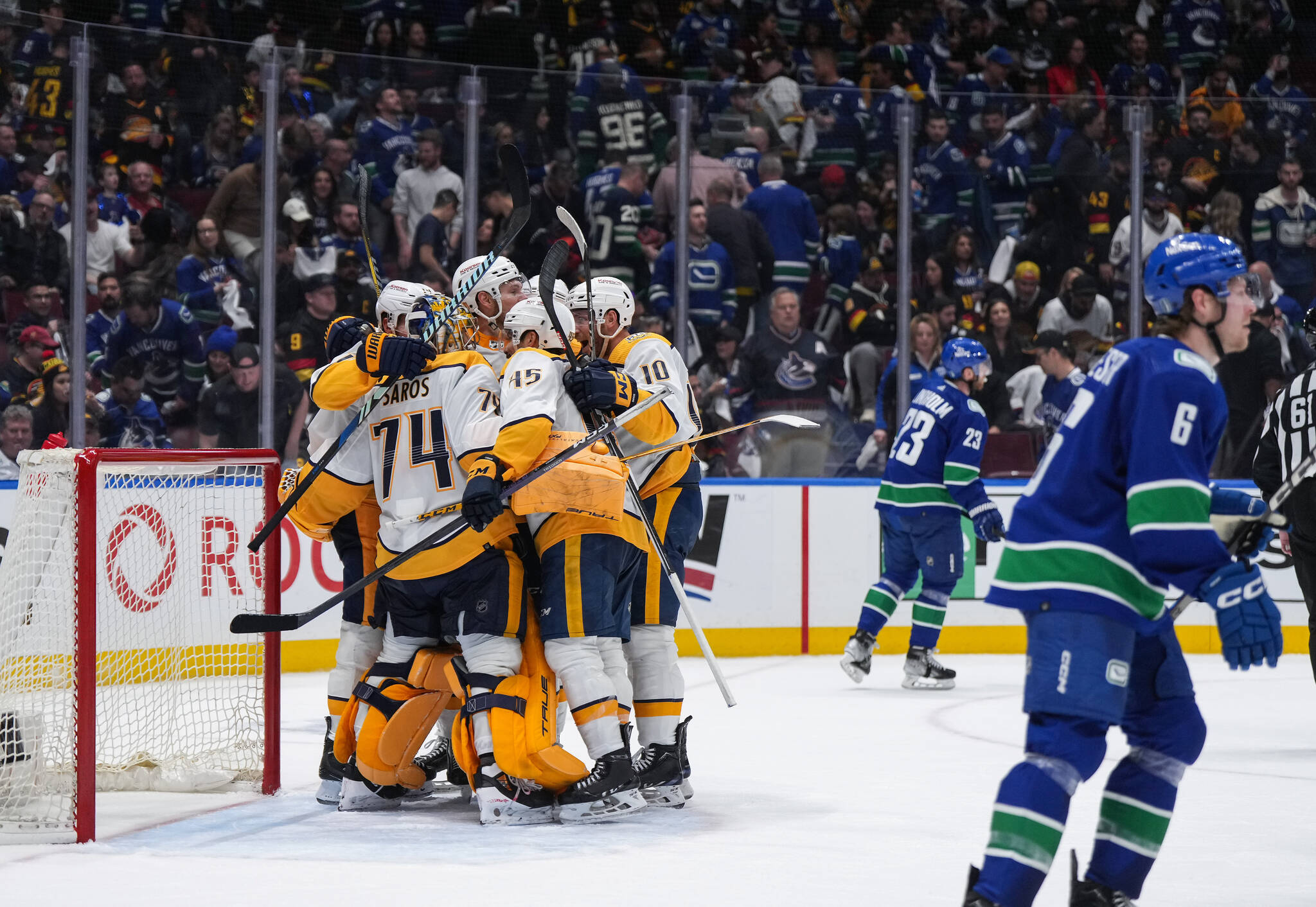 Nashville Predators players celebrate with goalie Juuse Saros (74) as Vancouver Canucks’ Elias Lindholm (23) and Brock Boeser (6) skate off the ice after Nashville defeated Vancouver 2-1 during Game 5 of an NHL hockey Stanley Cup first-round playoff series, in Vancouver, on Tuesday, April 30, 2024. THE CANADIAN PRESS/Darryl Dyck