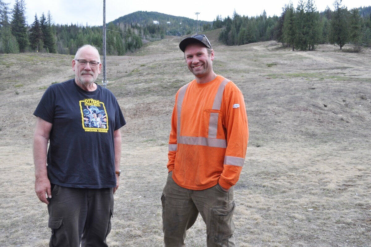 Wally (left) and Levi Huser stand with Salmo Ski Hill in the background. The community hill was open only 14 days last season. Photo: Tyler Harper
