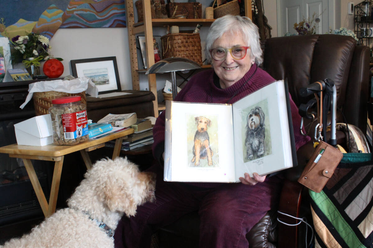 For Elain Genser, canine companionship is an important part of her life. Genser holds up paintings she has done of her past pets. (Samantha Duerksen/Black Press Media)