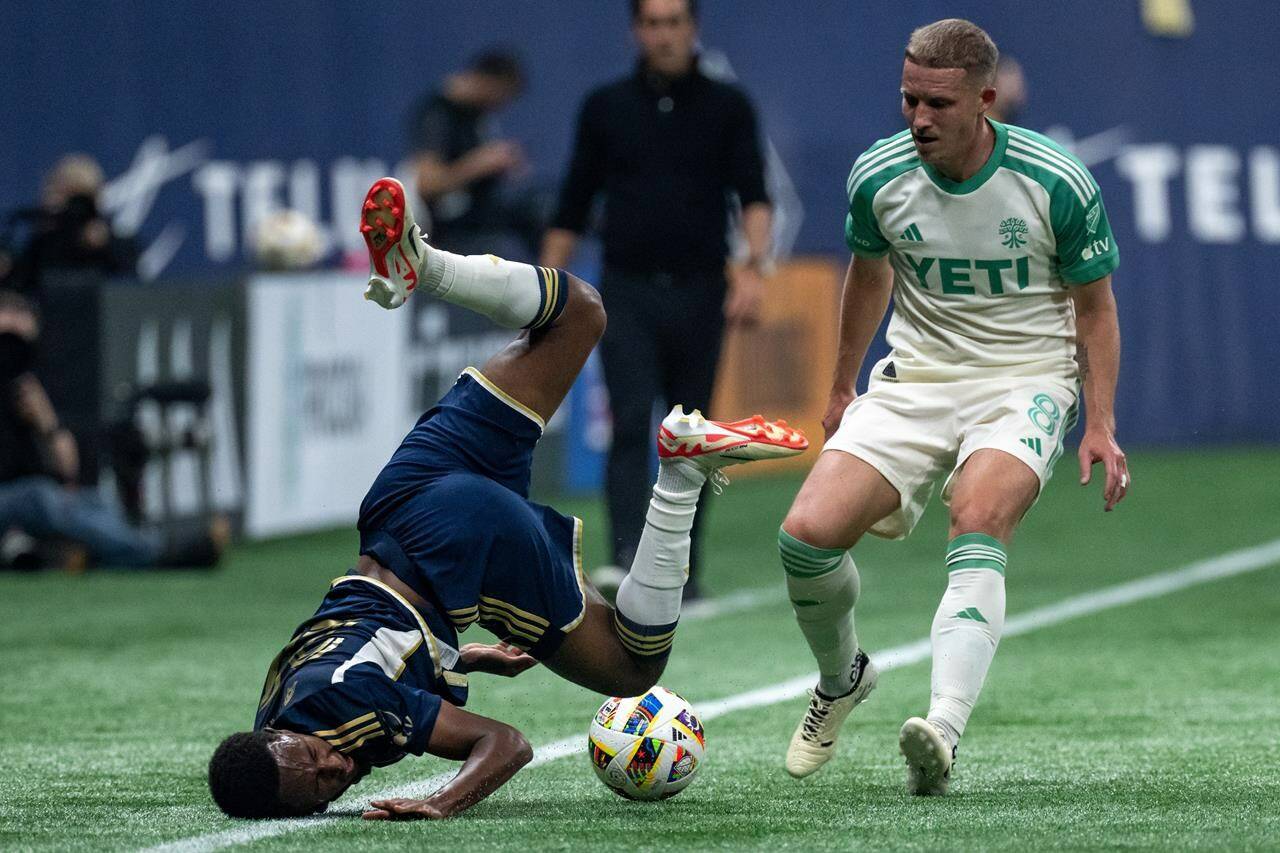 Vancouver Whitecaps’ Ali Ahmed (left) falls in front of Austin FC’s Alexander Ring (8) as they vie for the ball during the first half of an MLS soccer match in Vancouver, on Saturday, May 4, 2024. THE CANADIAN PRESS/Ethan Cairns