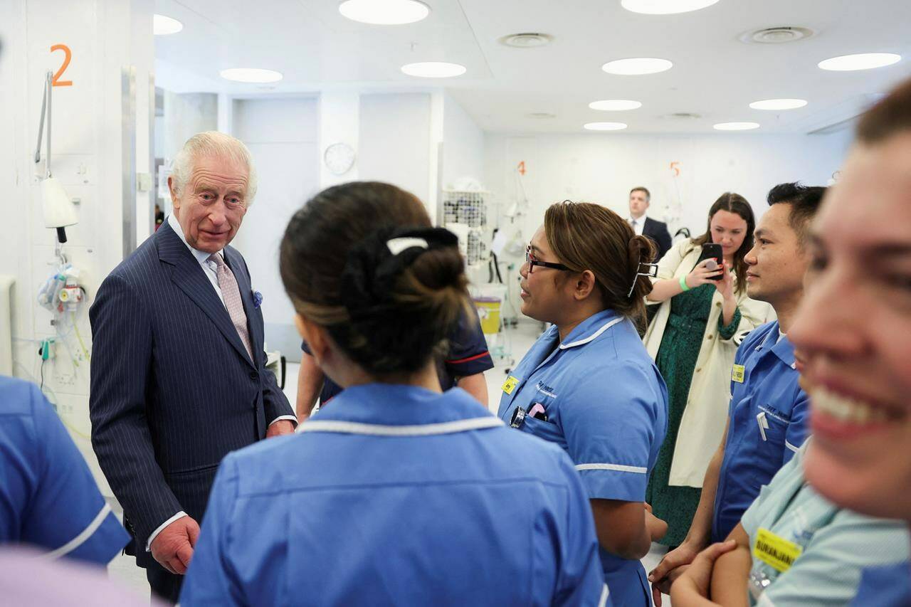 FILE - Britain’s King Charles III meets with staff members during a visit to the University College Hospital Macmillan Cancer Centre in London, Britain, Tuesday,April 30, 2024. King Charles III’s decision to be open about his cancer diagnosis has helped the new monarch connect with the people of Britain and strengthened the monarchy in the year since his dazzling coronation at Westminster Abbey. (Suzanne Plunkett/Pool photo via AP, File)