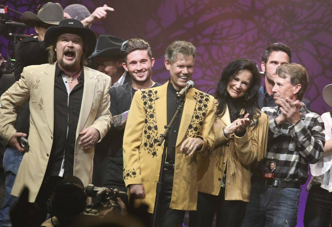 FILE - Travis Tritt, left, Randy Travis, center left, Mary Travis, center right, and Ricky Traywick, right, appear on stage at the “1 Night. 1 Place. 1 Time.: A Heroes and Friends Tribute to Randy Travis” on Feb. 8, 2017 in Nashville, Tenn. (Photo by Laura Roberts/Invision/AP, File)