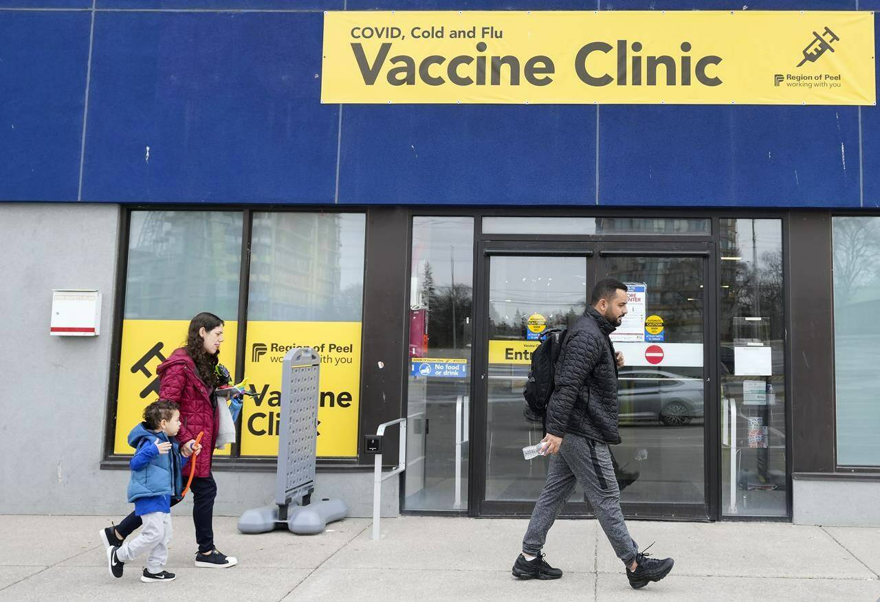 People walk past a vaccine clinic during the COVID-19 pandemic in Mississauga, Ont., on Wednesday, April 13, 2022. The federal government announced $574 million in funding on Monday for 19 projects across the country to help prepare for the next pandemic. THE CANADIAN PRESS/Nathan Denette