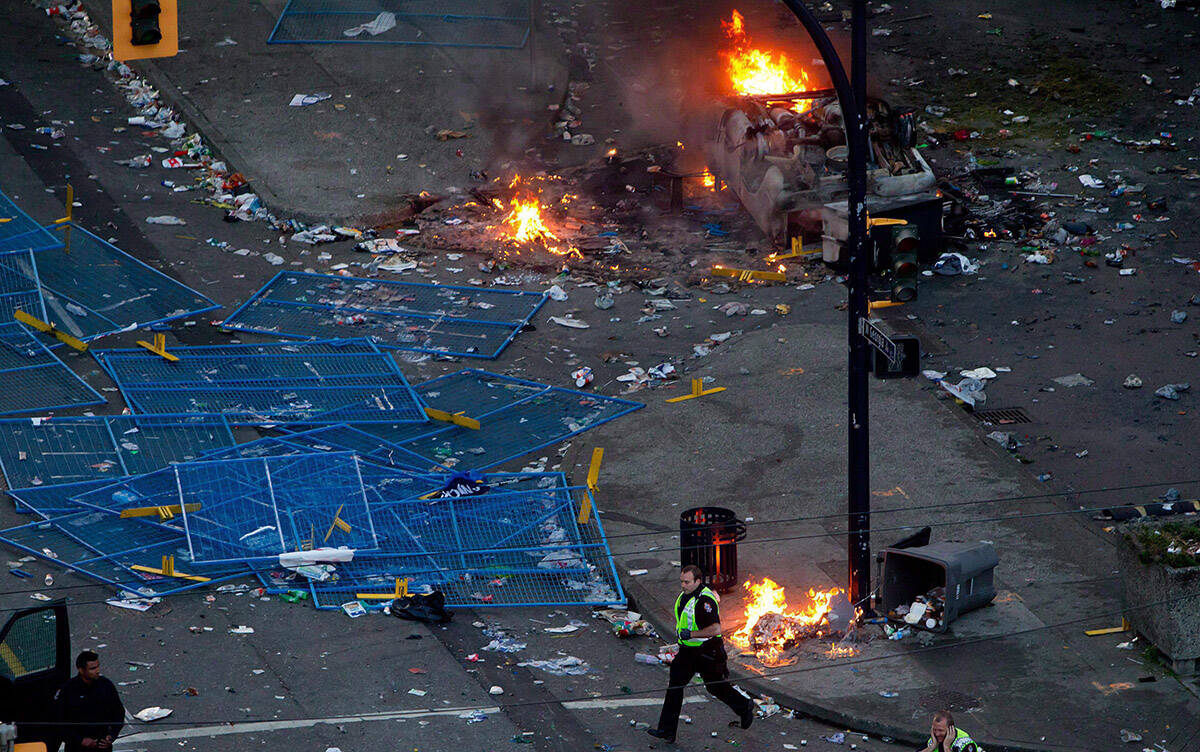 A police officer runs past debris and fires after rioters burned police cars after the Vancouver Canucks were defeated by the Boston Bruins in the NHL’s Stanley Cup Final in Vancouver, B.C., on Wednesday June 15, 2011. THE CANADIAN PRESS/Darryl Dyck