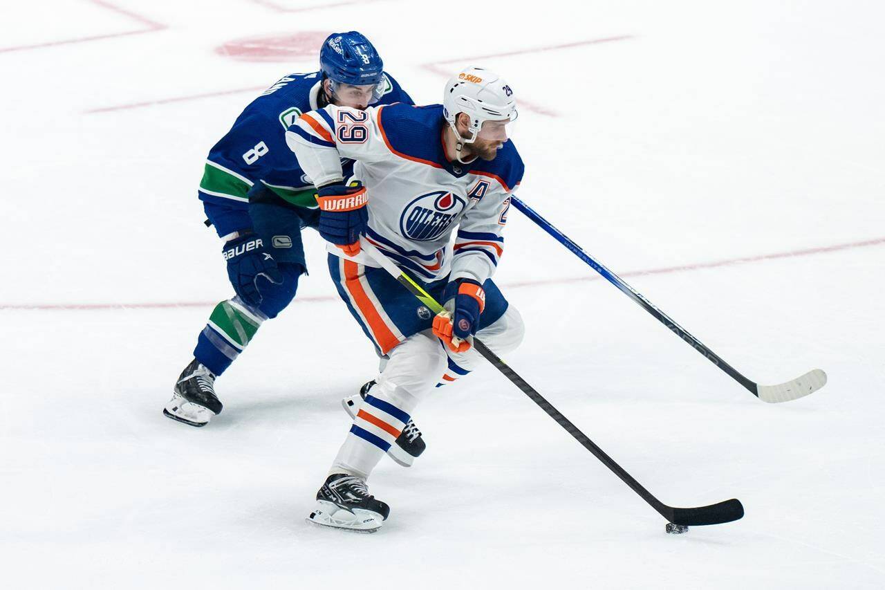 Edmonton Oilers’ Leon Draisaitl (29) skates with the puck while being watched by Vancouver Canucks’ Conor Garland (8) during the third period in Game 1 of an NHL hockey Stanley Cup second-round playoff series, in Vancouver, on Wednesday, May 8, 2024. THE CANADIAN PRESS/Ethan Cairns