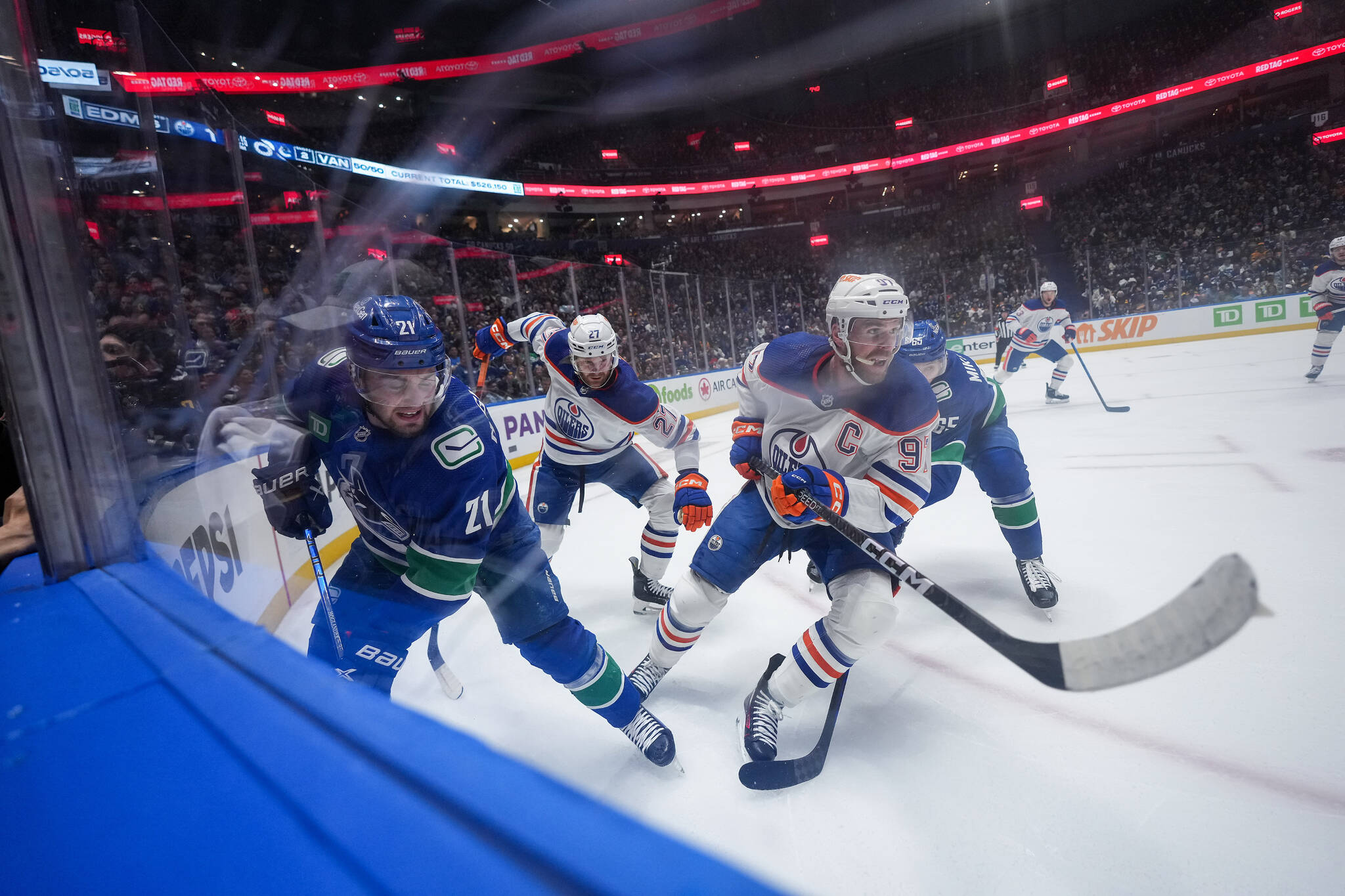 Vancouver Canucks’ Nils Hoglander (21) and Edmonton Oilers’ Connor McDavid (97) vie for the puck during the first period in Game 1 of an NHL hockey Stanley Cup second-round playoff series, in Vancouver, on Wednesday, May 8, 2024. THE CANADIAN PRESS/Darryl Dyck