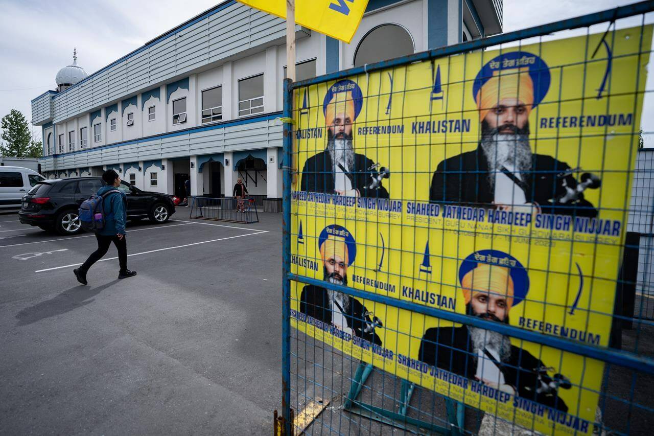 A person walks past signs showing Hardeep Singh Nijjar at the Guru Nanak Sikh Gurdwara in Surrey, B.C., on Friday, May 3, 2024. THE CANADIAN PRESS/Ethan Cairns