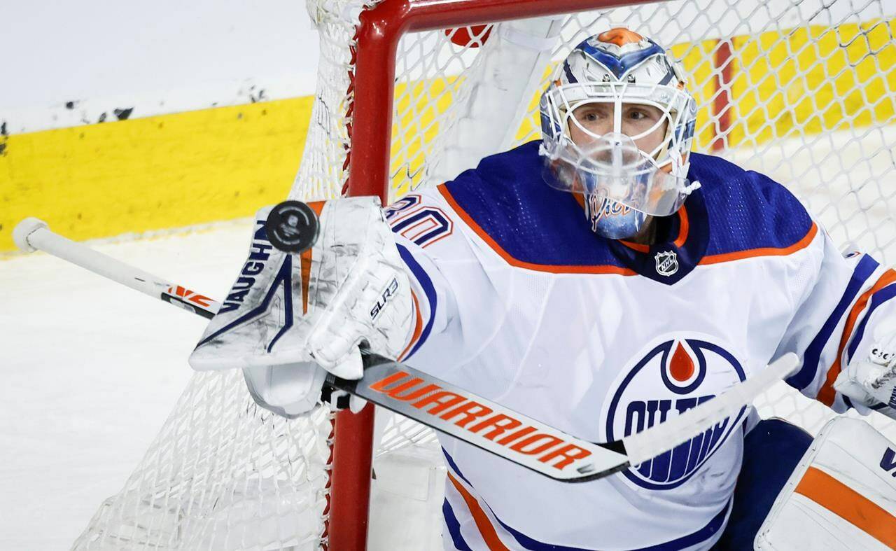 Edmonton Oilers goalie Calvin Pickard (30) swats away a shot during first period NHL hockey action against the Calgary Flames in Calgary on April 6, 2024. THE CANADIAN PRESS/Jeff McIntosh