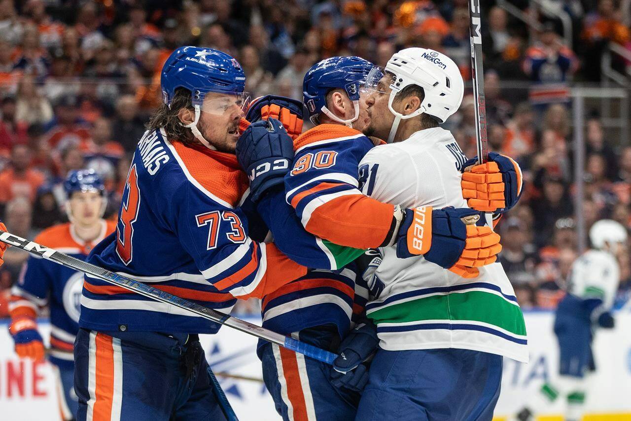 Vancouver Canucks' Dakota Joshua (81) roughs it up with Edmonton Oilers' Vincent Desharnais (73) and Corey Perry (90) during third period second-round NHL playoff action in Edmonton on Tuesday May 14, 2024.THE CANADIAN PRESS/Jason Franson