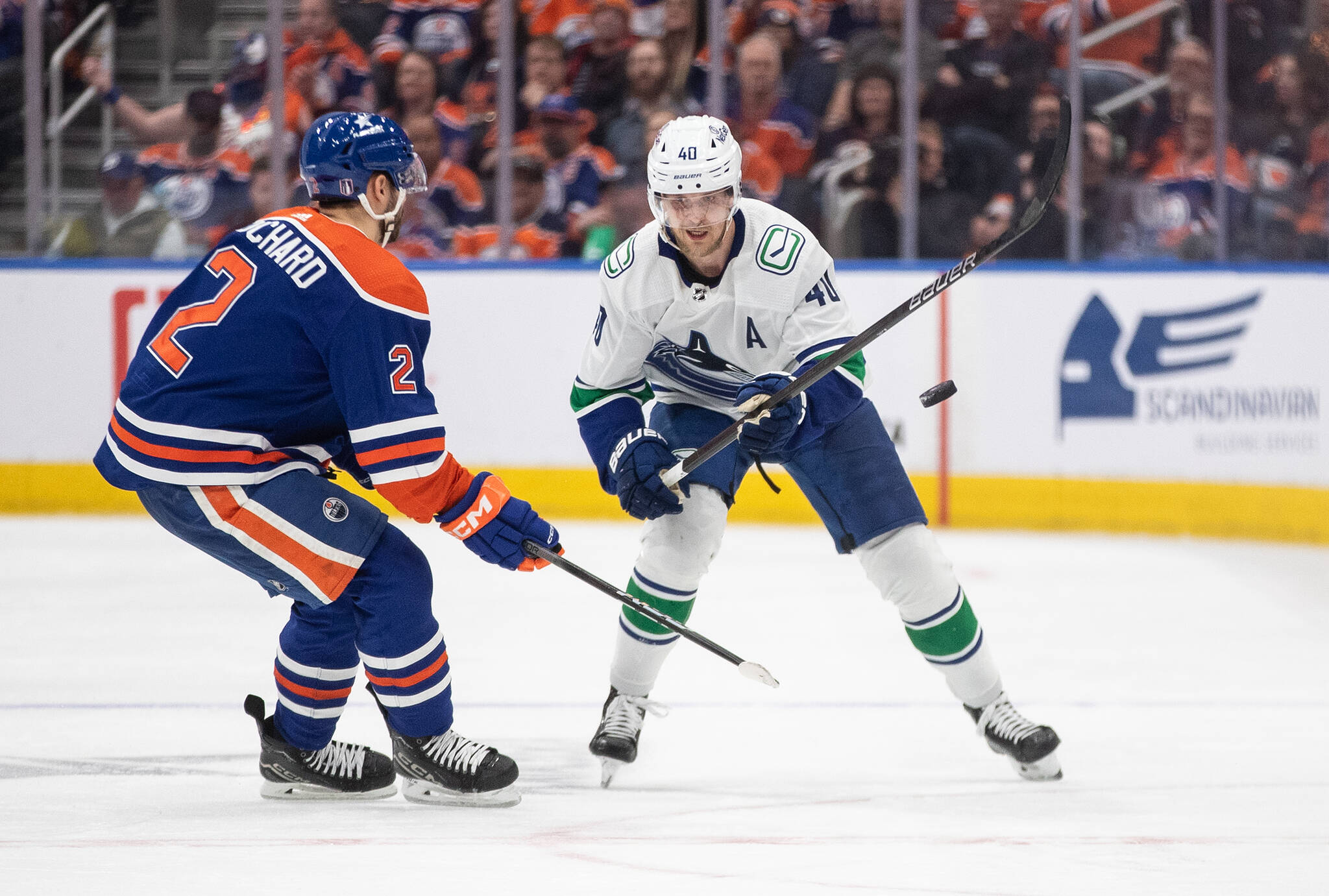 Vancouver Canucks’ Elias Pettersson (40) and Edmonton Oilers’ Evan Bouchard (2) battle for the puck during third period second-round NHL playoff action in Edmonton on Tuesday May 14, 2024.THE CANADIAN PRESS/Jason Franson
