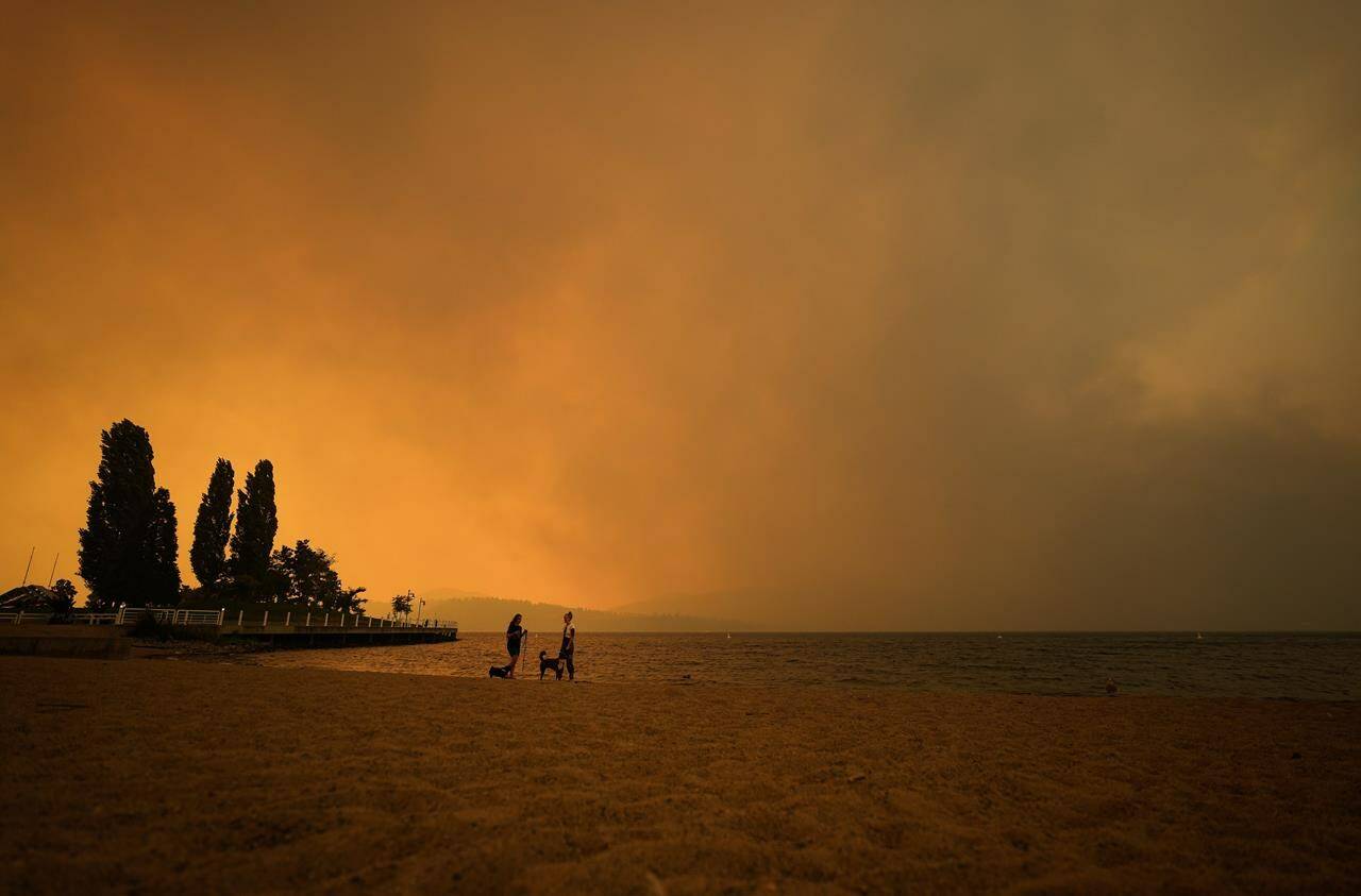 Smoke from the McDougall Creek wildfire fills the air and nearly blocks out the sun as people take in the view of Okanagan Lake from Tugboat Beach, in Kelowna, B.C., on August 18, 2023. THE CANADIAN PRESS/Darryl Dyck