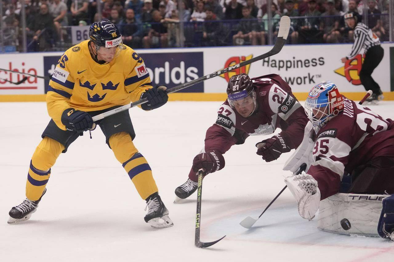 Latvia’s Eriks Vitols, right, makes a save in front of Sweden’s Andre Burakovsky, left, during the preliminary round match between Latvia and Sweden at the Ice Hockey World Championships in Ostrava, Czech Republic, Saturday, May 18, 2024. (AP Photo/Darko Vojinovic)