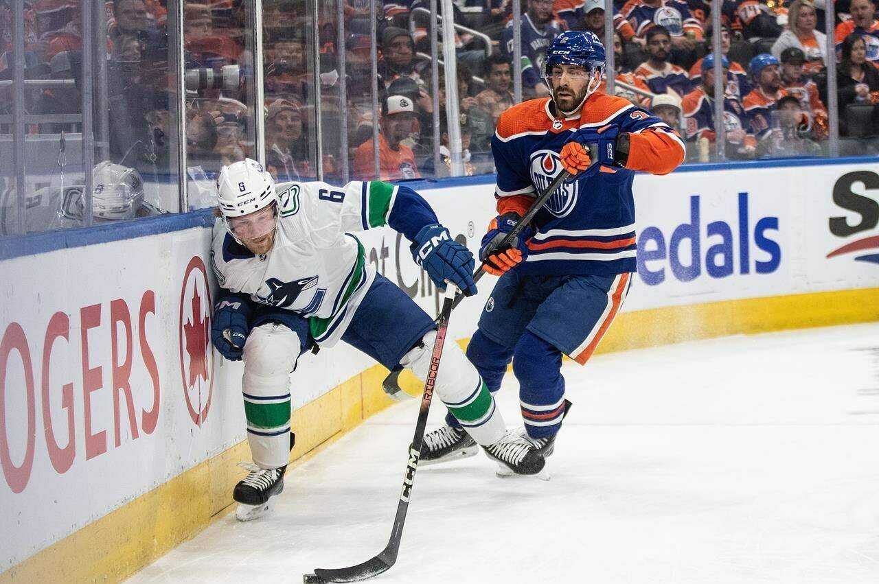 Vancouver Canucks’ Brock Boeser (6) and Edmonton Oilers’ Evan Bouchard (2) battle for the puck during first period second-round NHL playoff action in Edmonton on Saturday May 18, 2024. THE CANADIAN PRESS/Jason Franson