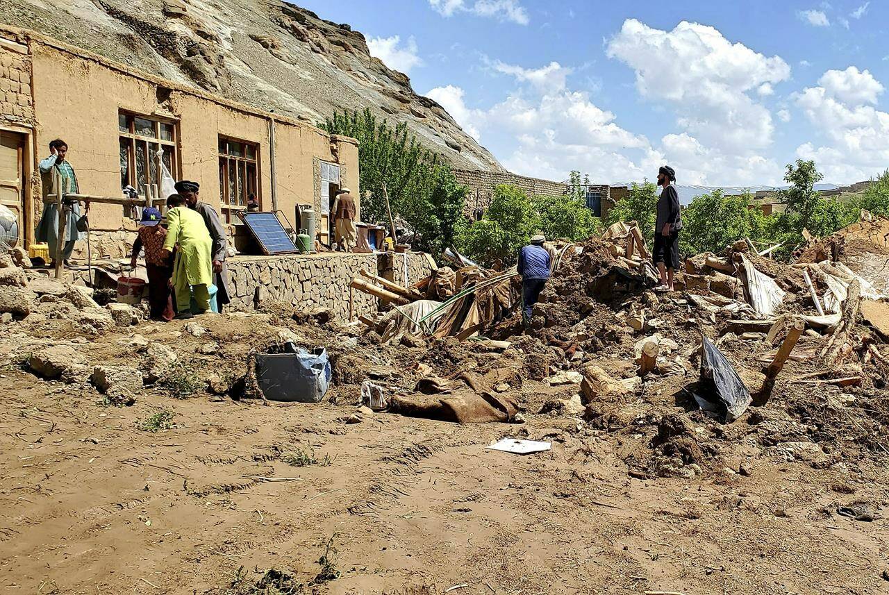 Afghan men collect their belongings from their damaged home after heavy flooding in Ghor province in western Afghanistan, Saturday, May 18, 2024. Flash floods from heavy seasonal rains in Ghor province killed dozens of people and dozens remain missing, a Taliban official said on Saturday, adding the death toll was based on preliminary reports and might rise. (AP Photo/Omid Haqjoo)