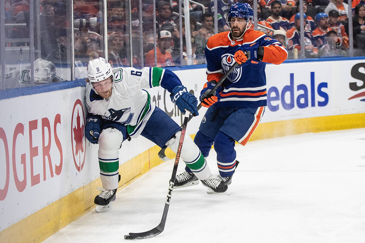 Vancouver Canucks’ Brock Boeser (6) and Edmonton Oilers’ Evan Bouchard (2) battle for the puck during first period second-round NHL playoff action in Edmonton on Saturday May 18, 2024.THE CANADIAN PRESS/Jason Franson