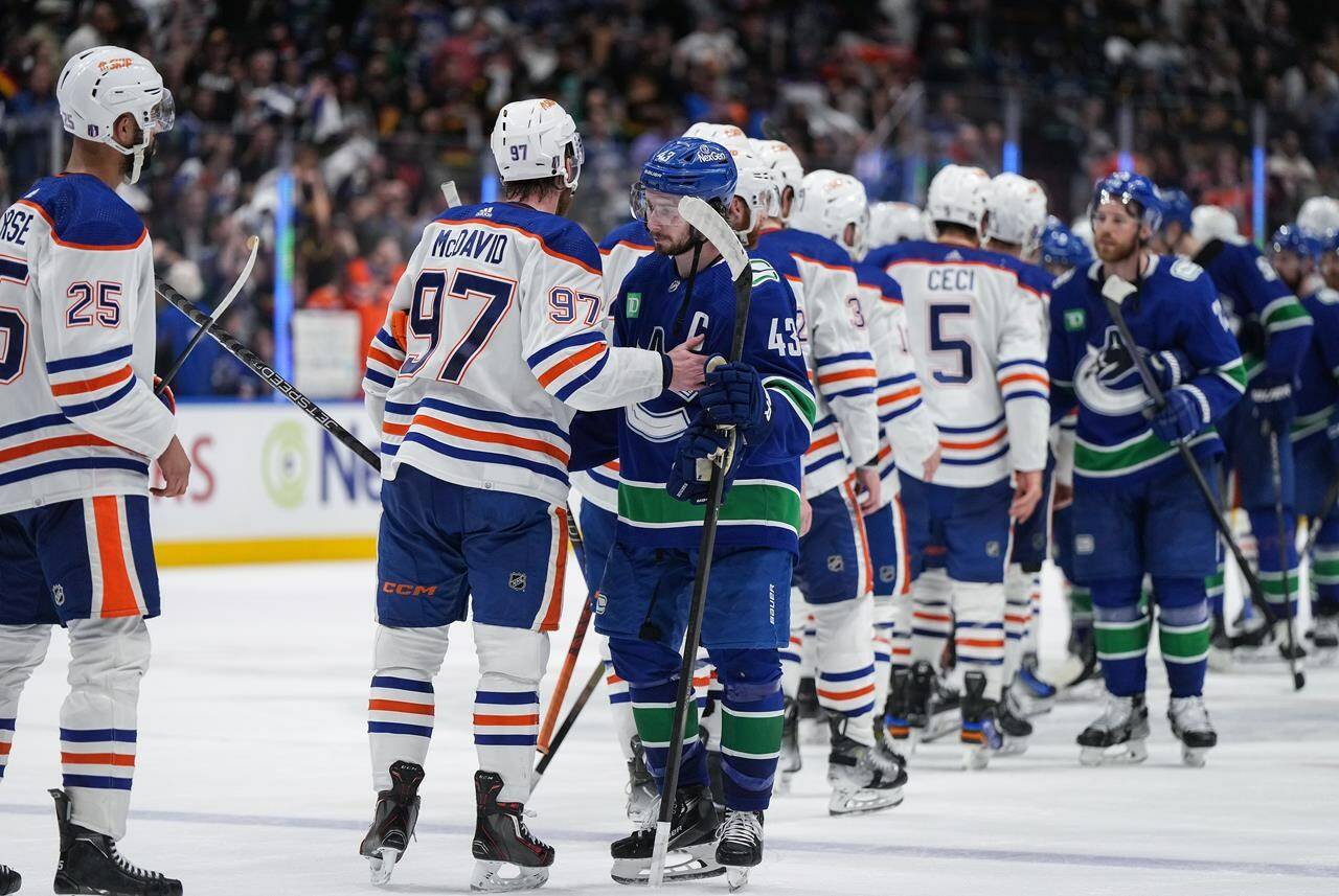 Vancouver Canucks’ Quinn Hughes (43) and Edmonton Oilers’ Connor McDavid (97) talk while shaking hands after Edmonton defeated Vancouver during Game 7 of an NHL hockey Stanley Cup second-round playoff series, in Vancouver, on Monday, May 20, 2024. THE CANADIAN PRESS/Darryl Dyck