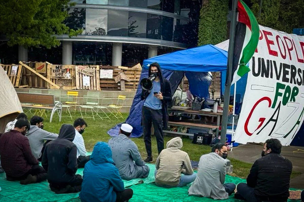 Prayer at UBCO encampment on Friday May 18, with caption “If our loved ones in Gaza can pray in the rubble, we can pray in the rain.” (@peoplesuniversityubco/Instagram)