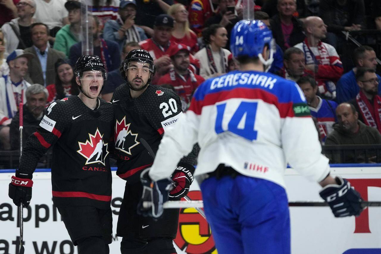 Slovakia’s Peter Ceresnak, right, skates past as Canada’s Nick Paul, center, celebrates with Canada’s Bowen Byram after scoring his sides third goal during the quarterfinal match between Canada and Slovakia at the Ice Hockey World Championships in Prague, Czech Republic, Thursday, May 23, 2024. (AP Photo/Petr David Josek)