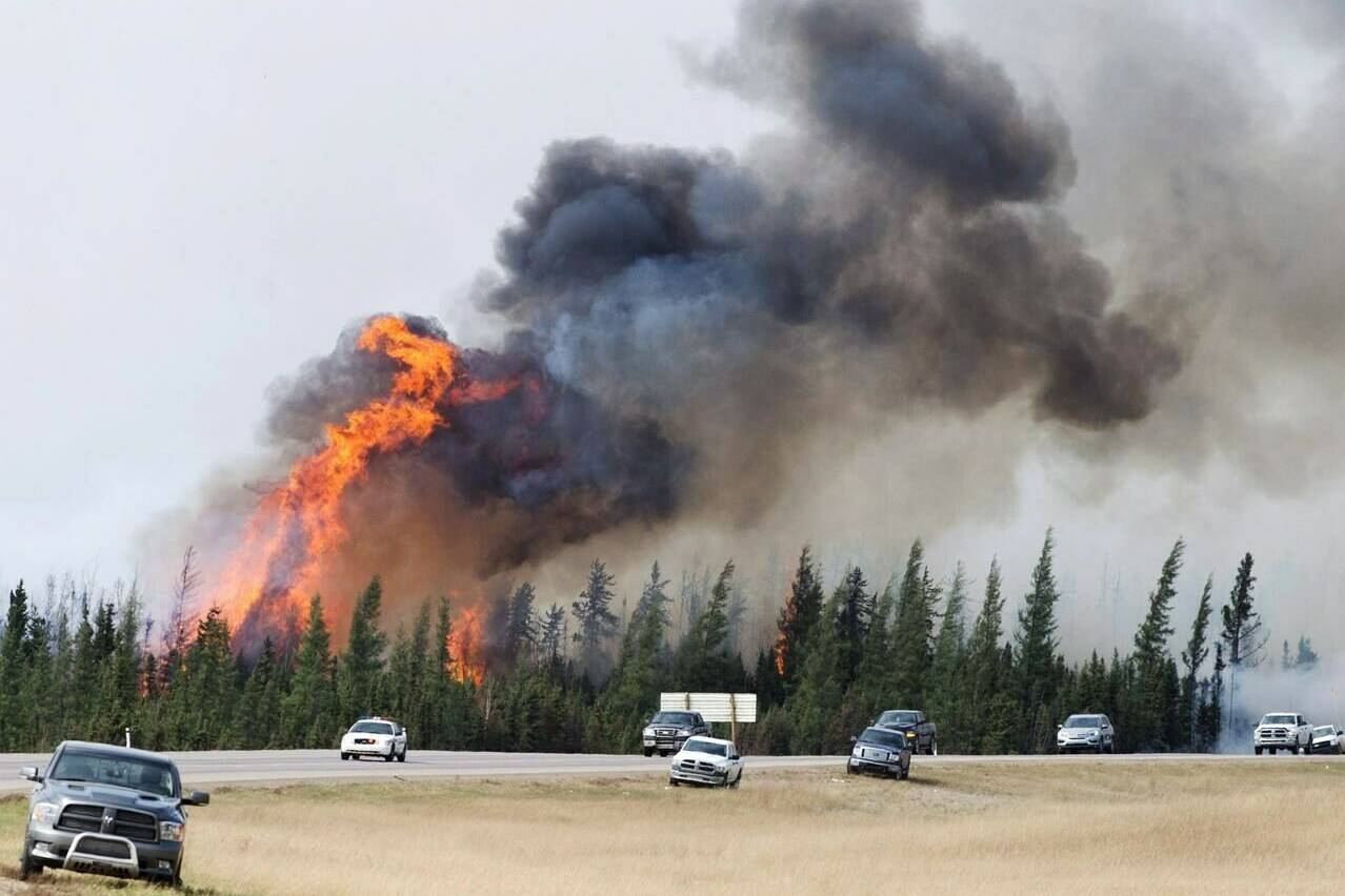 RCMP escort evacuees from Fort McMurray, Alberta past wildfires that were still burning out of control Saturday, May 7, 2016. THE CANADIAN PRESS/Ryan Remiorz