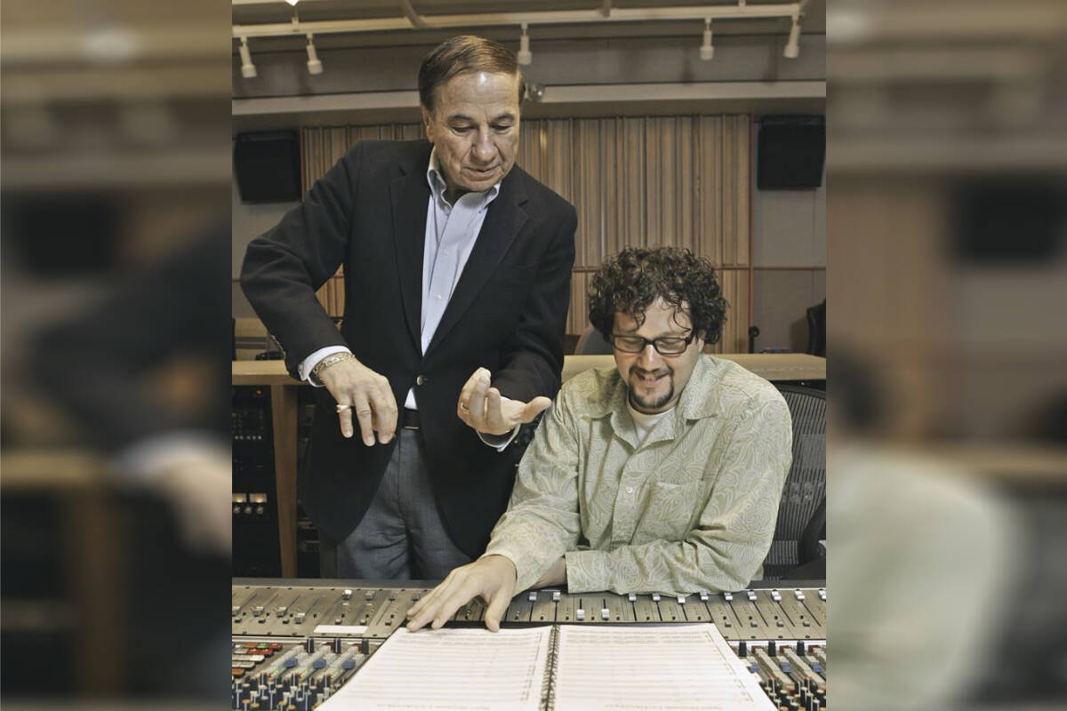 FILE - Composers Richard M. Sherman, left, who, along with his brother Robert, wrote the song “It’s a Small World” for the Disneyland ride of the same name, and Michael Giacchino, right, who composed the driving music for Disneyland’s newly-redesigned “Space Mountain” ride, work in a sound room at Walt Disney Imagineering offices in Glendale, Calif., July 5, 2005. Sherman, one half of the prolific, award-winning pair of brothers who helped form millions of childhoods by penning classic Disney tunes, died Saturday, May 25, 2024. He was 95. (AP Photo/Kevork Djansezian, File)