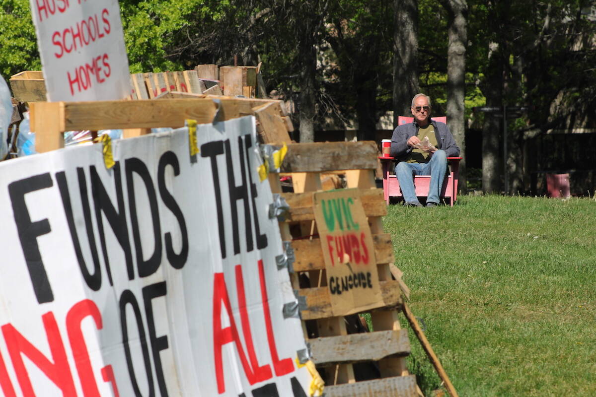 A man sits in a chair beside the Palestinian solidarity encampment at the University of Victoria on May 17. (Jake Romphf/News Staff)