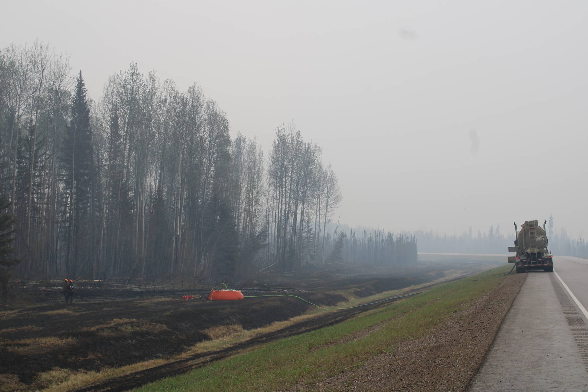 Firefighters working the Parker Lake wildfire are seen in a staging area along Highway 97 looking south with a water bladder and fire hose set up among charred grassland in a May 15, 2024, handout photo. THE CANADIAN PRESS/HO-BC Wildfire Service
