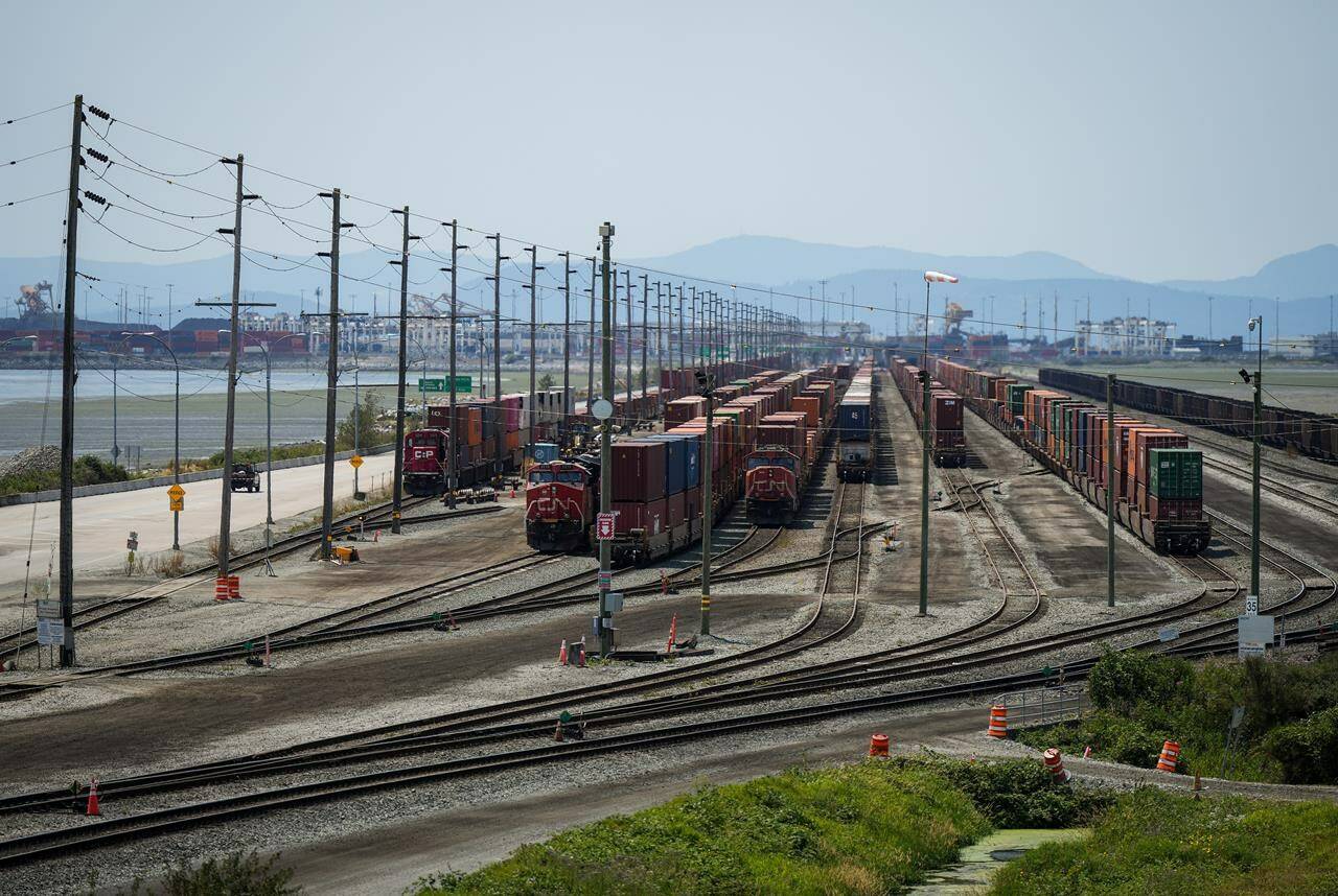 Trains are seen as cargo containers sit idle on rail tracks in Delta, B.C., on Friday, July 7, 2023. The U.S. Department of Justice in Washington State says two men are facing human smuggling charges for their alleged role in a scheme to get people across the Canada-U.S. border in B.C. on freight trains. THE CANADIAN PRESS/Darryl Dyck