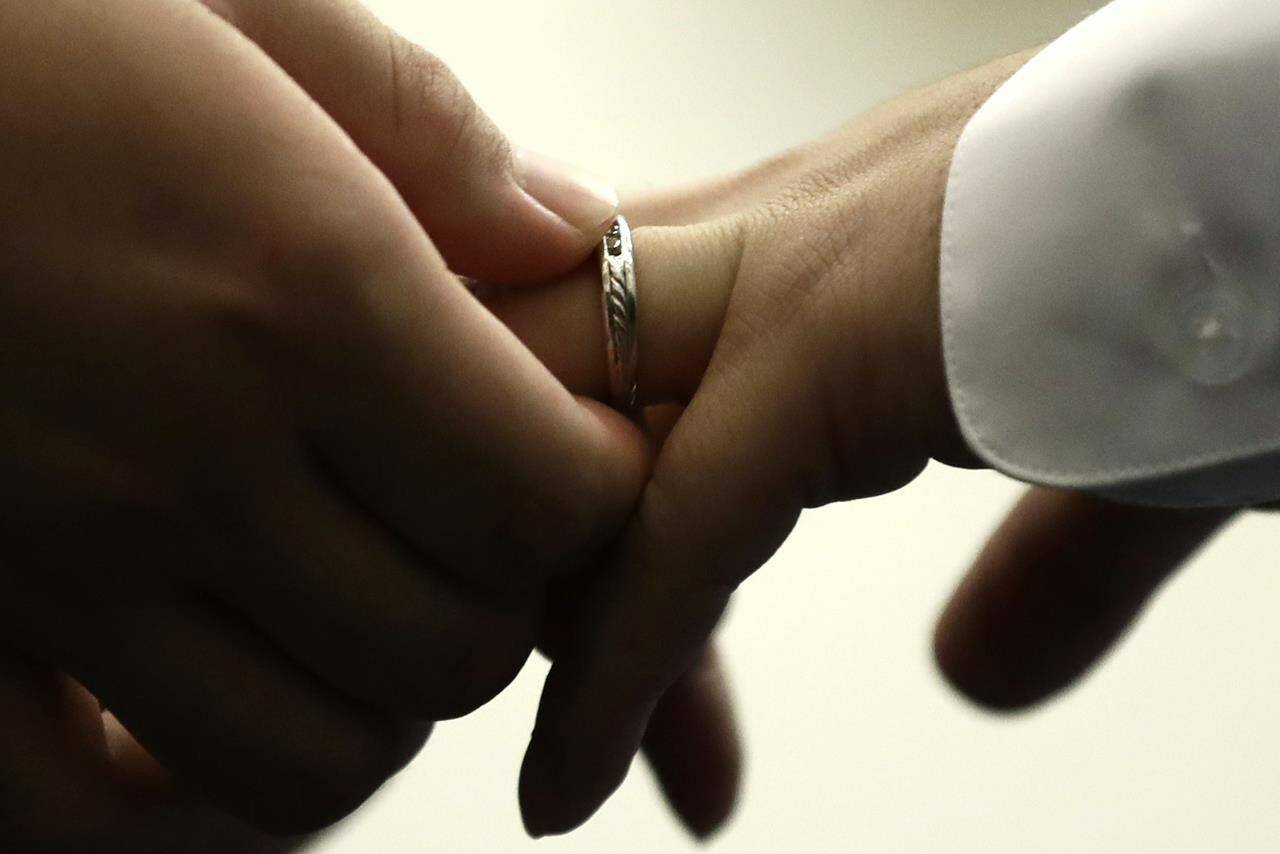 FILE - A couple exchanges wedding bands at City Hall in Philadelphia on Oct. 11, 2018. Divorce registries are part of a trend toward breaking the stigma of broken marriages, along with divorce parties and formal divorce announcements akin to wedding and marriage news. (AP Photo/Matt Rourke, File)