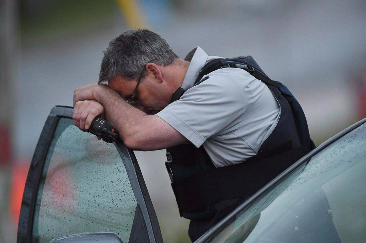 Almost 10 years after a disturbed man with a rifle killed three Mounties in Moncton, N.B., the RCMP have yet to fully implement a key recommendation from a 2014 review aimed at preventing such deadly encounters. An RCMP officer rests his head at a roadblock in Moncton, N.B. on Thursday, June 5, 2014. THE CANADIAN PRESS/Andrew Vaughan