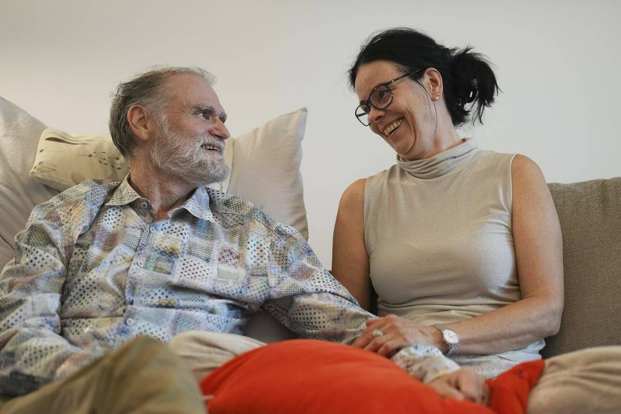 Michael Bommer, left, who is terminally ill with colon cancer, looks at his wife Anett Bommer during a meeting with The Associated Press at his home in Berlin, Germany, Wednesday, May 22, 2024. Bommer, who has only a few more weeks to live, teamed up with friend who runs the AI-powered legacy platform Eternos to “create a comprehensive, interactive AI version of himself, allowing relatives to engage with his life experiences and insights,” after he has passed away. (AP Photo/Markus Schreiber)