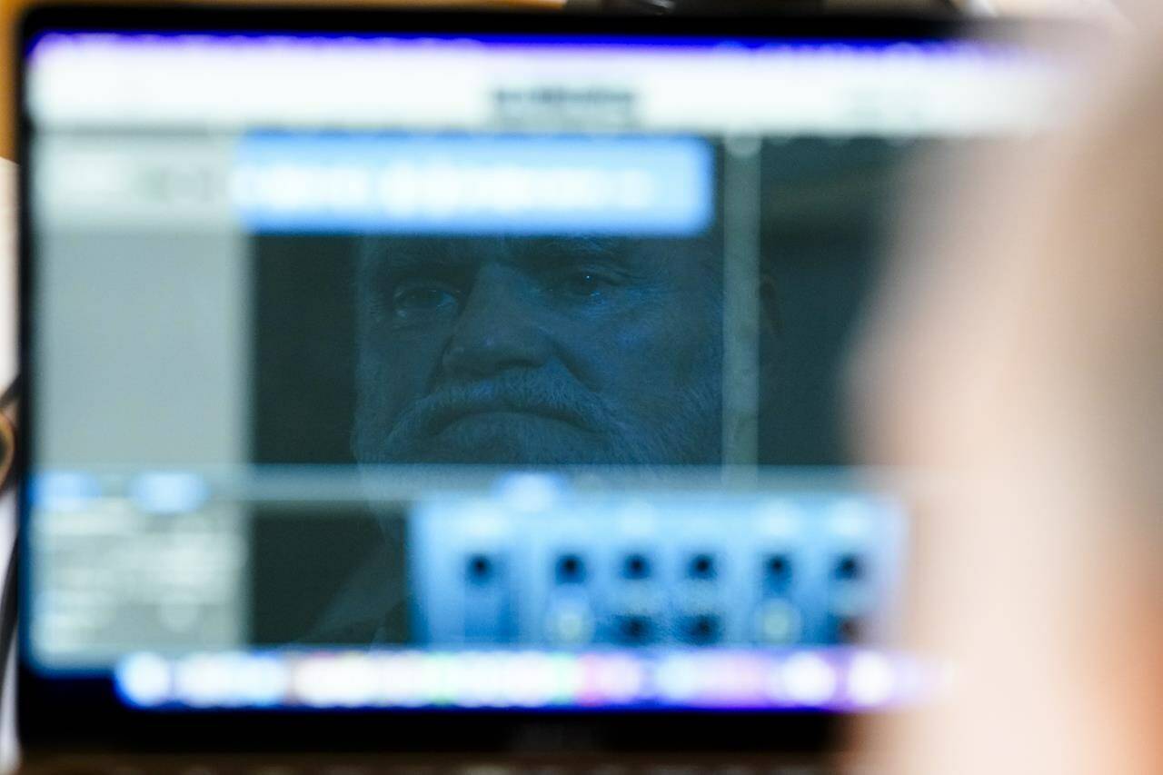 Michael Bommer, who is terminally ill with colon cancer, is reflected in his computer screen during a meeting with The Associated Press at his home in Berlin, Germany, Wednesday, May 22, 2024. Bommer, who has only a few more weeks to live, teamed up with friend who runs the AI-powered legacy platform Eternos to “create a comprehensive, interactive AI version of himself, allowing relatives to engage with his life experiences and insights,” after he has passed away. (AP Photo/Markus Schreiber)