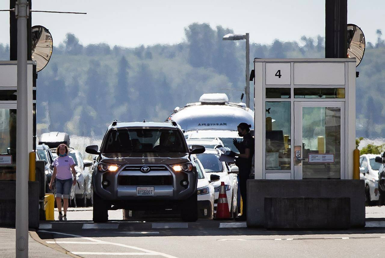 A Canada Border Services Agency officer speaks to a motorist entering Canada at the Douglas-Peace Arch border crossing, in Surrey, B.C., on Monday, August 9, 2021. The union representing thousands of Canadian border workers says they will begin job action Friday afternoon if no deal is reached by then. THE CANADIAN PRESS/Darryl Dyck
