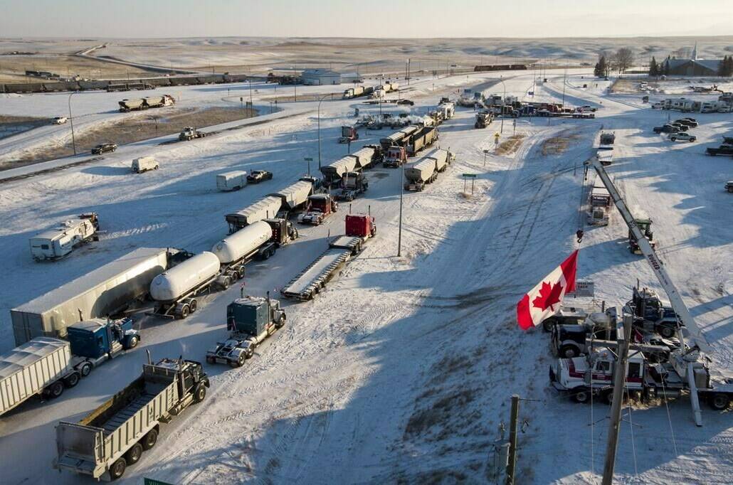 A truck convoy of anti-COVID-19 vaccine mandate demonstrators block the highway at the busy Canada-U.S. border crossing in Coutts, Alta., Wednesday, Feb. 2, 2022. THE CANADIAN PRESS/Jeff McIntosh